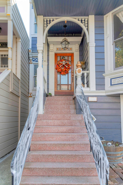 Фиолетовый дом с украшениями для празднования Хэллоуина у дверей в Сан-Франциско, Калифорния. Впереди лестница с фальшивыми паутинами на перилах, ведущая к деревянной входной двери с венком.. - Фото, изображение
