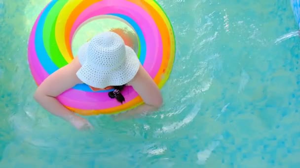 Meisje met een regenboog opblaasbare ring in het zwembad.slow motion. Kinderzwemmen in het zwembad.Zomer en vakantie. - Video