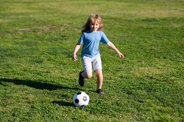 Soccer kid boy playing football. Child boy play football on outdoor field. Children score goal at soccer game. Cute boy kicking soccer ball. - Foto, afbeelding