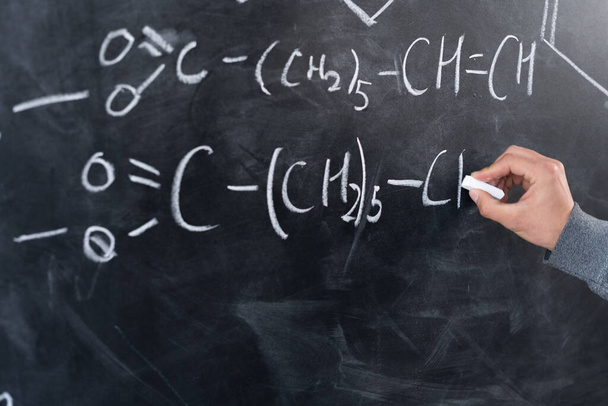 study of chemistry concept, chemist hand draws formulas and elements with chalk on the blackboard, signs and symbols of chemistry, organic science, lesson at school - Foto, imagen