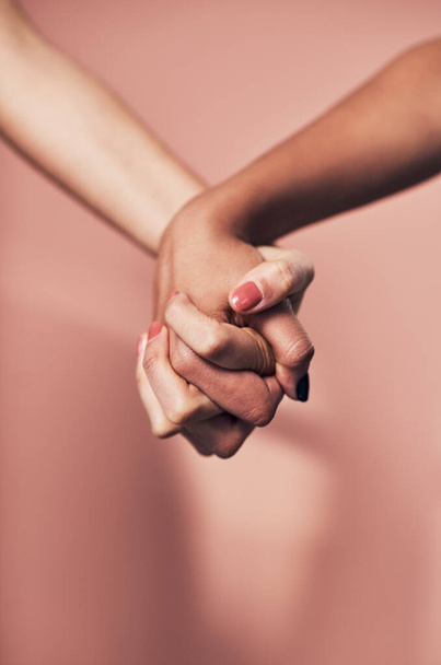 Pystyimme niin paljon, kun seisomme yhdessä. Kaksi tunnistamatonta naista, jotka pitelevät toisiaan kädestä pinkkiä taustaa vasten.. - Valokuva, kuva