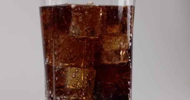 Pouring dark soda drink in tall glass with ice cube bubble fizz macro closeup - Séquence, vidéo