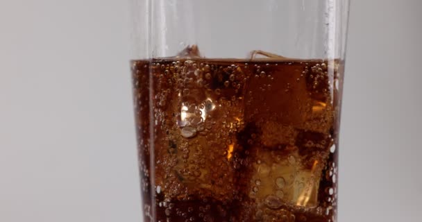 Nalanie ciemnego napoju gazowanego w wysokiej szklance z bąbelkami lodu musujące makro zbliżenie - Materiał filmowy, wideo