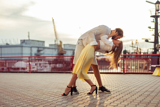 港で日没時にキスをする若いカップル、男と女。ロマンチックな愛の概念 - 写真・画像