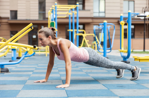 Active lifestyle. Fit woman push ups on outdoor workout playground - Foto, afbeelding