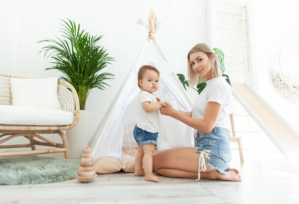 Happy woman mom and her little daughter at home in Children's room with wigwam. Maternal care concept. Spend time together. Loving family.  - Photo, image