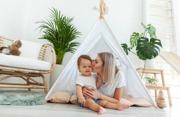 Young mother and little daughter spend time together in a wigwam at home - Foto, Bild