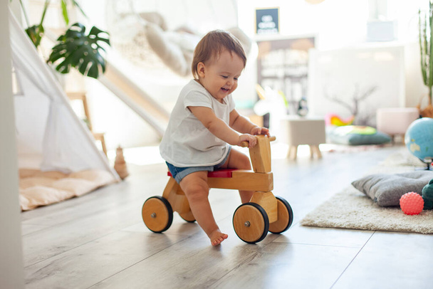 Bambina su uno scooter in legno nella stanza dei bambini - Foto, immagini