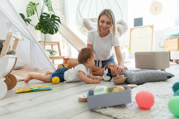 Cute young mother with her little daughter are playing in the playroom with toys. Motherhood - Foto, Imagen