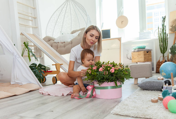 Mom with little baby daughter celebrate birthday with bouquet of roses at home - Photo, Image