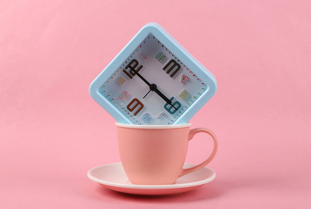 Empty cup with alarm clock on pink background - Foto, imagen