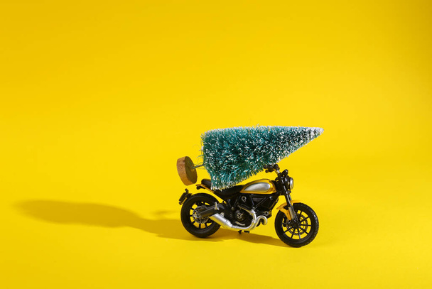 Motorcycle model with a Christmas tree on a yellow background. Minmal merry christmas layout - 写真・画像