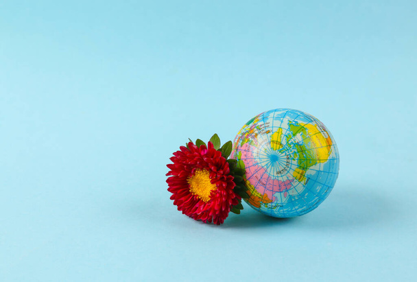 Aarde Dag. Globe met bloem op blauwe achtergrond - Foto, afbeelding