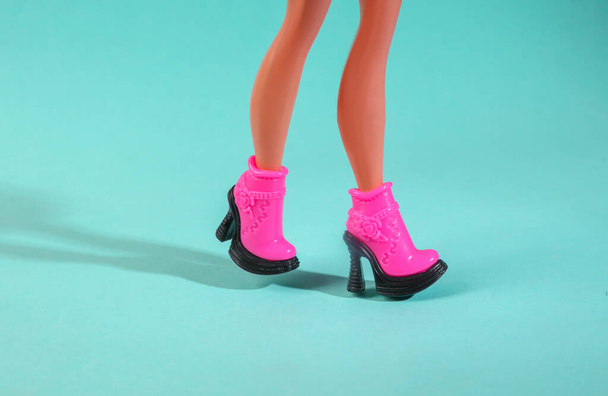 Doll legs in trendy boots on a blue background. Minimal fashion layout - Foto, afbeelding