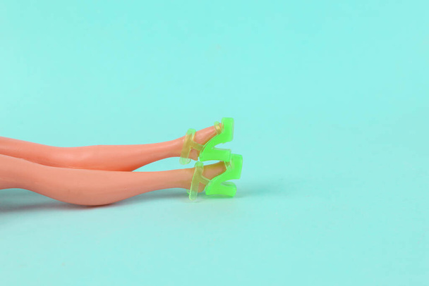 Poppenpootjes in trendy sandalen op een blauwe achtergrond. Minimale modelbaan - Foto, afbeelding
