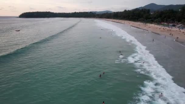 Surffaajat saavat aaltoja auringonlaskun aikaan. Näkymä lennokista - Materiaali, video