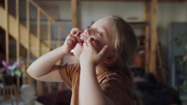 子供は楽しんでいる。彼女は恐ろしい顔をし、指でまぶたを広げます。高品質4k映像 - 映像、動画