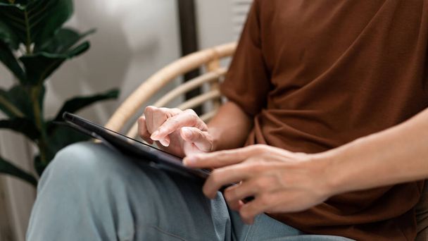 Концепція технології Чоловік з його повсякденною футболкою і джинсами сидить зручно на дерев'яному стільці і робить сенсорний екран для перевірки веб-браузера на iPad
. - Фото, зображення