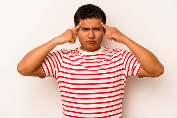 Young hispanic man isolated on white background focused on a task, keeping forefingers pointing head. - Photo, Image