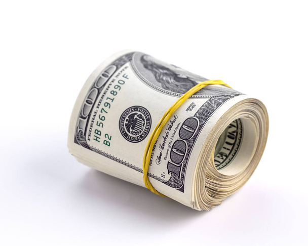 Roll of one hundred dollars american banknotes wrapped with a yellow elastic isolated on a white background. Close-up. Has a clipping path saved. - Foto, afbeelding