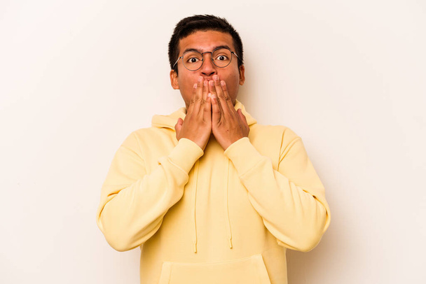 Junger hispanischer Mann isoliert auf weißem Hintergrund schockiert Mund mit Händen bedecken. - Foto, Bild