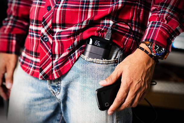 L'homme chargeant son smartphone avec une banque d'alimentation noire. Faible profondeur de champ focalisée sur l'affichage de la banque de puissance. - Photo, image
