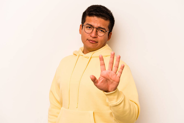Joven hombre hispano aislado sobre fondo blanco rechazando a alguien mostrando un gesto de disgusto. - Foto, Imagen