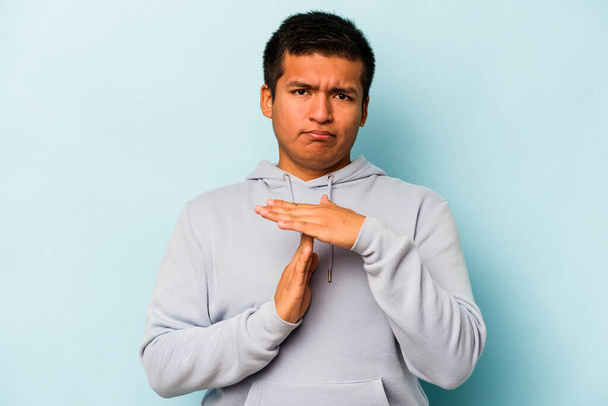 Mladý hispánec muž izolovaný na modrém pozadí ukazující timeout gesto. - Fotografie, Obrázek