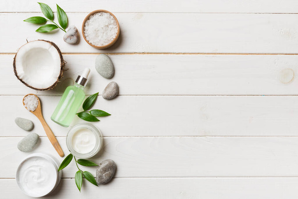 Coconut with jars of coconut oil and cosmetic cream on colored background. Top view. Free space for your text. Natural spa coconut cosmetics and organic treatment concept Coconut Spa composition. - 写真・画像