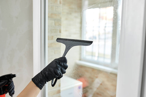 Professional Siivous palveluyrityksen työntekijä kumihanskat poistaa likaa ikkunoista mopilla, lähikuva - Valokuva, kuva