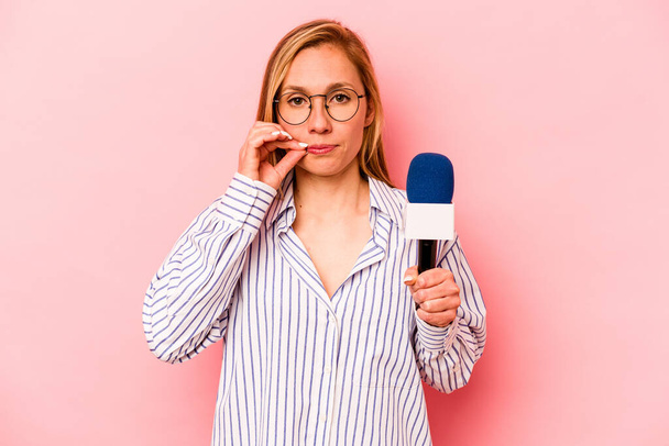 Young caucasian TV presenter woman isolated on pink background with fingers on lips keeping a secret. - Foto, Imagem