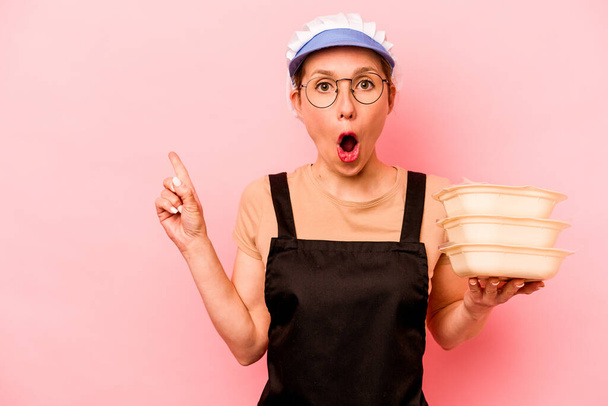 Young cook volunteer woman isolated on pink background pointing to the side - Photo, image