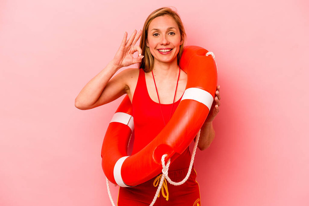 Young caucasian life guard woman isolated on pink background cheerful and confident showing ok gesture. - Photo, Image