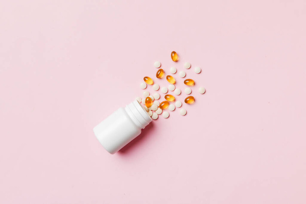 Multicolored pills and capsules in plastic bottle on Colored background, copy space. Many different various medicine tablets and pills, vitamin and nutritional supplements concept. - Foto, afbeelding