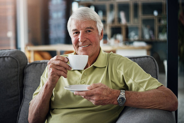 Afternoon tea always goes down well. Portrait of a senior man enjoying a beverage while relaxing on the sofa at home. - Photo, Image