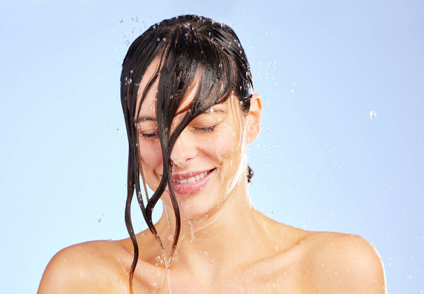 Vergessen Sie nicht, all die Negativität wegzuwaschen. Aufnahme einer jungen Frau, die sich unter der Dusche vor blauem Hintergrund die Haare wäscht. - Foto, Bild