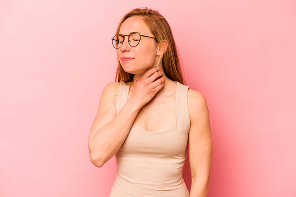 Jonge blanke vrouw geïsoleerd op roze achtergrond lijdt pijn in de keel als gevolg van een virus of infectie. - Foto, afbeelding
