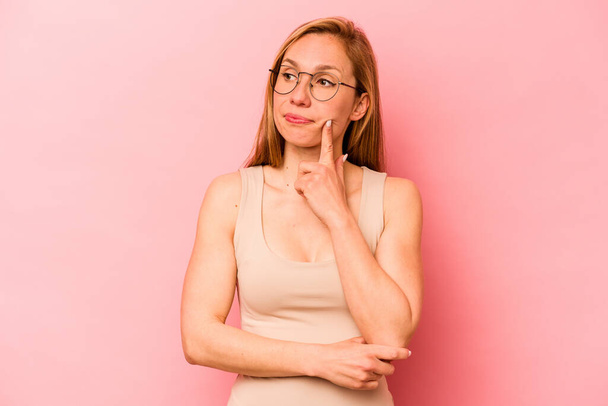 Young caucasian woman isolated on pink background contemplating, planning a strategy, thinking about the way of a business. - Valokuva, kuva
