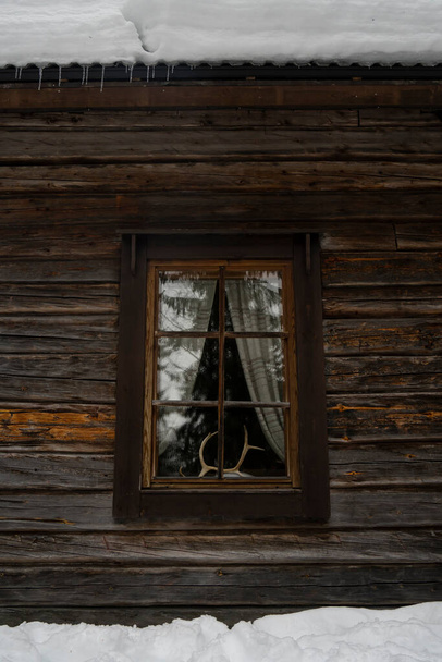 Ren geyiği boynuzları karlı bir günde dekorasyon için ahşap bir kulübe penceresi takar.. - Fotoğraf, Görsel