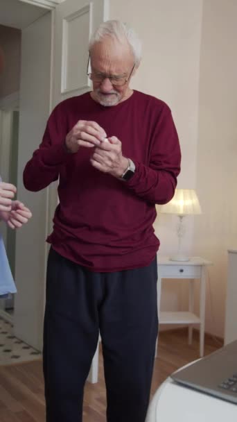 Ο συνταξιούχος προσλαμβάνεται από τον εκπαιδευτή. Μια γυναίκα βοηθάει έναν γέρο να βάλει ακουστικά στα αυτιά του. Παίζει βίντεο γυμναστικής στον υπολογιστή της.. Υψηλής ποιότητας υλικό FullHD - Πλάνα, βίντεο