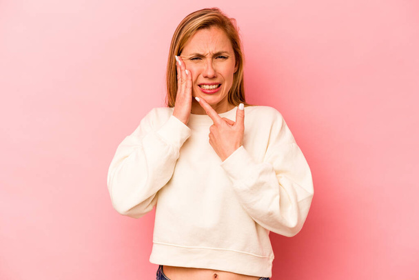 Mujer joven caucásica aislada sobre fondo rosa con un fuerte dolor de dientes, dolor molar. - Foto, imagen