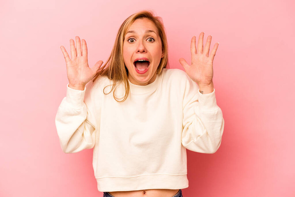 Young caucasian woman isolated on pink background receiving a pleasant surprise, excited and raising hands. - Fotografie, Obrázek