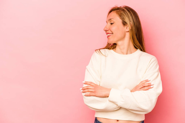 Young caucasian woman isolated on pink background smiling confident with crossed arms. - Photo, Image