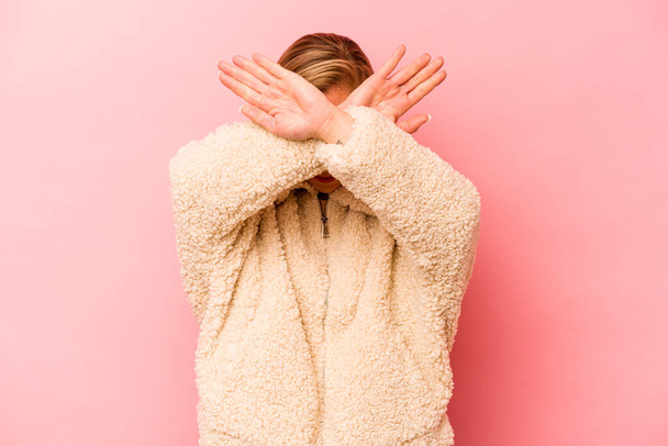 Young caucasian woman isolated on pink background keeping two arms crossed, denial concept. - Fotografie, Obrázek