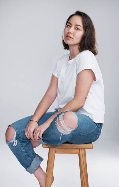 Keep it simple, keep it you. Cropped shot of a beautiful young woman sitting against a white background. - Фото, изображение