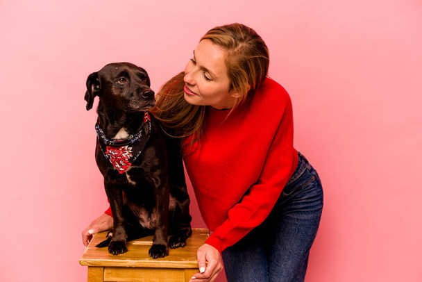 Young caucasian woman with her dog isolated on pink background - Photo, Image