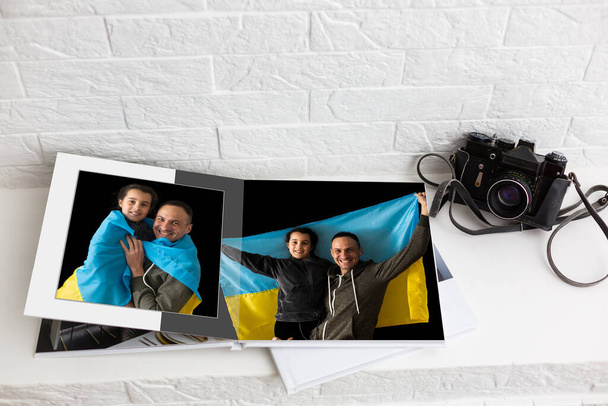 на белом столе открытая фотокнига с фотосессии семьи с украинским флагом - Фото, изображение