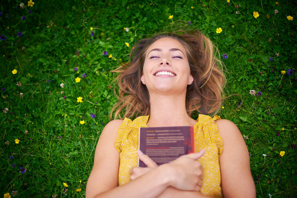 Taky chci žít šťastně až do smrti. Vysoký úhel záběr bezstarostné mladé ženy relaxující na trávě s knihou. - Fotografie, Obrázek
