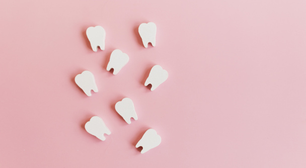 Witte tanden op een roze achtergrond met kopieerruimte. Tandheelkunde, tandheelkundige kliniek concept. - Foto, afbeelding