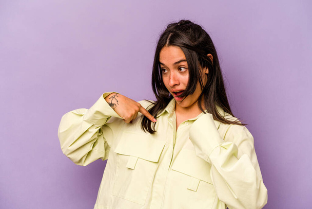 Young hispanic woman isolated on purple background surprised pointing with finger, smiling broadly. - Фото, изображение